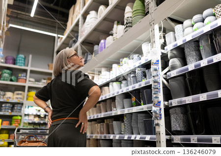 Woman shopping for pots and pans in a home goods store, exploring the colorful selection of kitchen 136246079