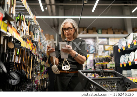 Senior woman shopping for kitchen utensils in a home goods store during the afternoon 136246120