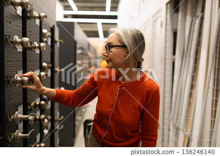 Woman selecting hardware in a home improvement store during daytime Woman selecting hardware in a home improvement store during daytime 136246140