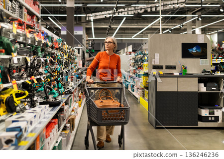 Woman shopping in a hardware store during the day, exploring various tools and equipment on the Woman shopping in a hardware store during the day, exploring various tools and equipment on the 136246236