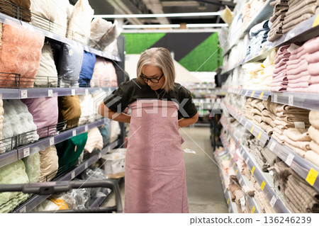 Woman shopping for fabric in a textile store while trying on a pink fabric wrap during daytime 136246239