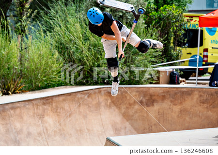 Young man practicing Scootering (Freestyle Scootering) in the new SkatePark in the central park of Igualada, Barcelona, Spain Young man practicing Scootering (Freestyle Scootering) in the new SkatePark in the central park of Igualada, Barcelona, Spain 136246608