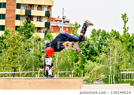 Young man practicing Scootering (Freestyle Scootering) in the new SkatePark in the central park of Igualada, Barcelona, Spain Young man practicing Scootering (Freestyle Scootering) in the new SkatePark in the central park of Igualada, Barcelona, Spain 136246614
