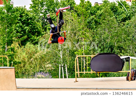 Young man practicing Scootering (Freestyle Scootering) in the new SkatePark in the central park of Igualada, Barcelona, Spain 136246615