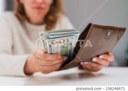 Close up of woman saving cash dollars in wallet. Financial planning and emergency fund concept. Close up of woman saving cash dollars in wallet. Financial planning and emergency fund concept. 136246671