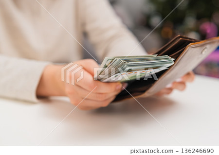 Female hands organizing cash money and saving dollars in wallet. Household budget and expense control. 136246690