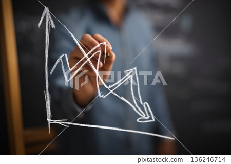A person draws a value line on a blackboard with chalk, indicating growth in data during a business meeting. The focus is on the upward trend and market assessment. A person draws a value line on a blackboard with chalk, indicating growth in data during a business meeting. The focus is on the upward trend and market assessment. 136246714