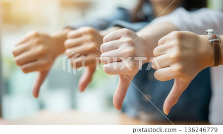 Several hands are shown prominently with thumbs pointing down. Friends gathered in a cafe express their opinions about the food or service while having a conversation. Several hands are shown prominently with thumbs pointing down. Friends gathered in a cafe express their opinions about the food or service while having a conversation. 136246779