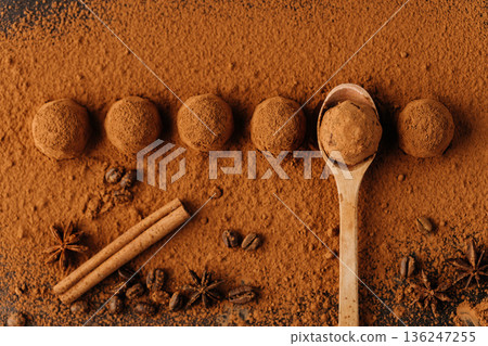 Cocoa dusted chocolate truffles in a row with wooden spoon, top view 136247255
