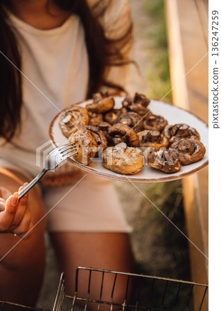 Grilled mushrooms on a plate at outdoor picnic, served with a fork 136247259