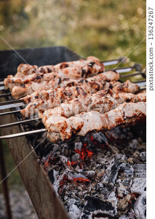 Pork shashlik on skewers grilling over hot charcoal outdoors, close up 136247267