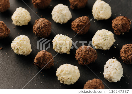 Close up of coconut and cocoa truffles on black background Close up of coconut and cocoa truffles on black background 136247287
