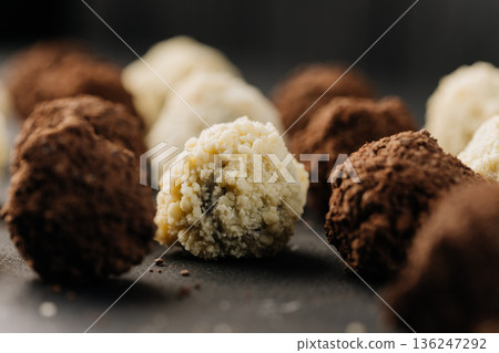 Macro coconut truffle with creamy center and cocoa truffles on dark slate Macro coconut truffle with creamy center and cocoa truffles on dark slate 136247292
