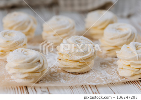 Vanilla zephyr marshmallow rosettes on parchment, soft pastel closeup 136247295