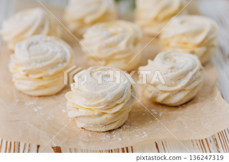 Vanilla zephyr marshmallow rosettes on parchment, soft pastel closeup 136247319