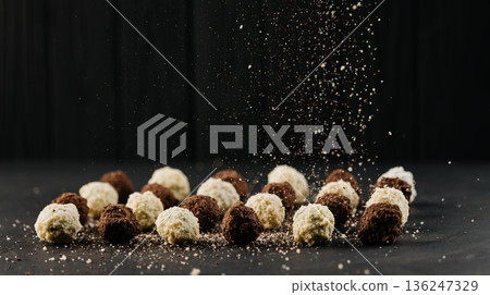 Assorted chocolate truffles with falling cocoa crumbs on dark background Assorted chocolate truffles with falling cocoa crumbs on dark background 136247329