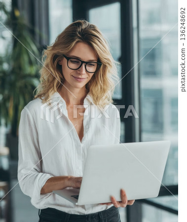 woman with glasses using laptop in office woman with glasses using laptop in office 136248692