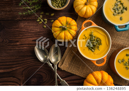 Pumpkin soup in ceramic bowls, wooden background, fresh pumpkins. Autumn food. Top view, copy space Pumpkin soup in ceramic bowls, wooden background, fresh pumpkins. Autumn food. Top view, copy space 136248895