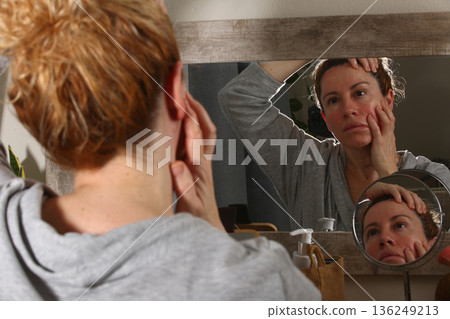 Mature Woman Practicing Face Yoga in Front of Mirror Mature Woman Practicing Face Yoga in Front of Mirror 136249213