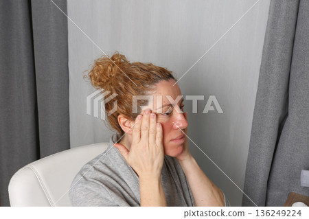 Mature Woman Practicing Face Yoga in Front of Mirror Mature Woman Practicing Face Yoga in Front of Mirror 136249224