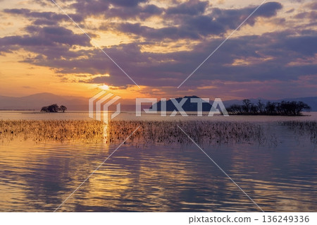 A winter sunset on Lake Biwa, a lakeside spot in Japan. A fantastical scene of withered lotus flowers and islands. 136249336