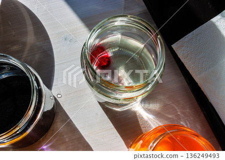 Top view of a glass jar of water with an red food dye tablet beginning to dissolve Top view of a glass jar of water with an red food dye tablet beginning to dissolve 136249493