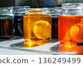 Close up of a easter egg in a yellow and orange food dye solution in a glass jars on a sunlit kitchen table 136249499