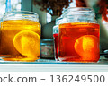 Close up of a easter egg in a yellow and orange food dye solution in a glass jars on a sunlit kitchen table 136249500