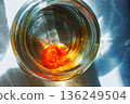 Top view into a glass jar of water with an orange food dye tablet dissolving at the bottom 136249504