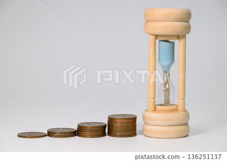 Long-term investment represented by an hourglass and stacks of coins 136251137