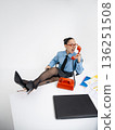 Young angry white woman in office attire working talking on vintage red phone, isolated on white background. In a blue shirt with a tie. Business occupation. Boss . 136251508