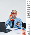 Young white woman in office attire working on laptop while talking on vintage red phone, isolated on white background 136251509
