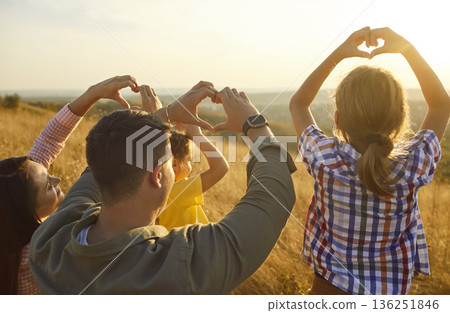 Happy family forming heart symbols at golden sunset over meadow, unity and joy 136251846