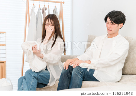 一對夫婦在客廳裡疊衣服(潮濕,有股霉味,在室內晾曬) 一對夫婦在客廳裡疊衣服(潮濕,有股霉味,在室內晾曬) 136251948