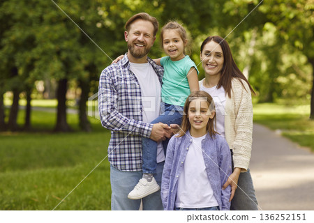 Portrait of happy smiling family with son and daughter standing in summer park together. 136252151