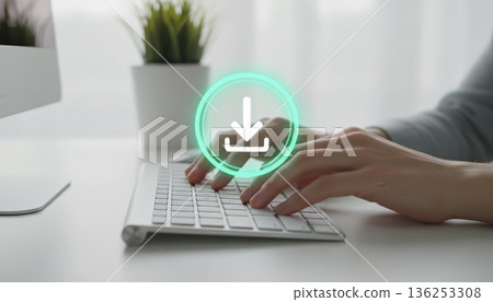 Hands typing on a computer keyboard with a glowing digital download icon overlaying, visualizing data transfer, internet connection, and software installation processes in a modern office setup 136253308