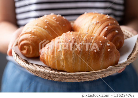 Salt bread (Shio pan) with sea salt flakes in a basket holding by woman hand, Japanese bakery style Salt bread (Shio pan) with sea salt flakes in a basket holding by woman hand, Japanese bakery style 136254762