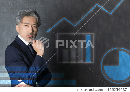 A gray-haired businessman thinking about business strategies while looking at graphs and charts, looking at the camera A gray-haired businessman thinking about business strategies while looking at graphs and charts, looking at the camera 136254987