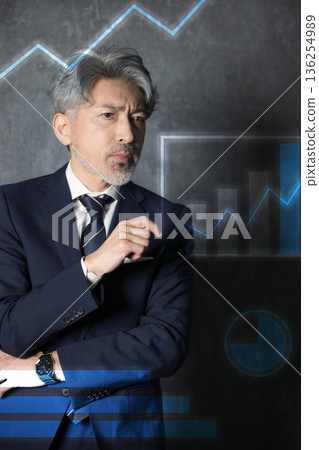A gray-haired businessman thinking about business strategies while looking at graphs and charts A gray-haired businessman thinking about business strategies while looking at graphs and charts 136254989