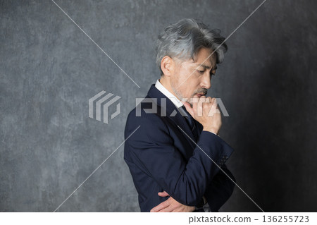 一位身著西裝的商務主管,手托下巴,若有所思。 一位身著西裝的商務主管,手托下巴,若有所思。 136255723