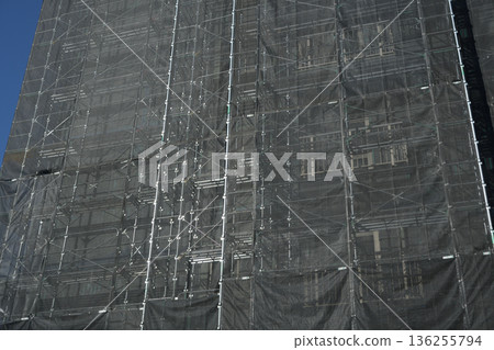 Scaffolding and black protective netting covering an apartment building undergoing major repair work03 Scaffolding and black protective netting covering an apartment building undergoing major repair work03 136255794