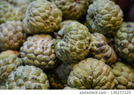 Juicy fruit with rough exterior. Aromatic cherimoya fruit displaying contrasting smooth inner pulp and coarse outer shell for visual storytelling Juicy fruit with rough exterior. Aromatic cherimoya fruit displaying contrasting smooth inner pulp and coarse outer shell for visual storytelling 136257120
