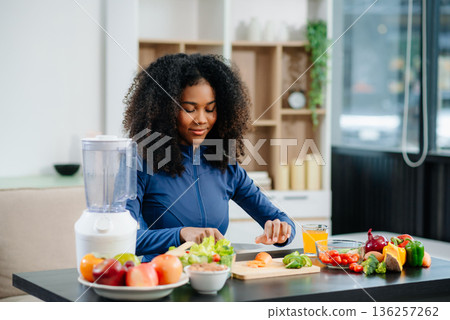 woman enjoys cherry tomatoes and salad in a cozy home kitchen surrounded by fruits, juice, and a blender. Perfect for health, diet, and clean eating concepts. woman enjoys cherry tomatoes and salad in a cozy home kitchen surrounded by fruits, juice, and a blender. Perfect for health, diet, and clean eating concepts. 136257262