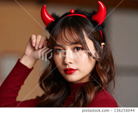A young woman wearing devil horns as a Halloween costume A young woman wearing devil horns as a Halloween costume 136258044