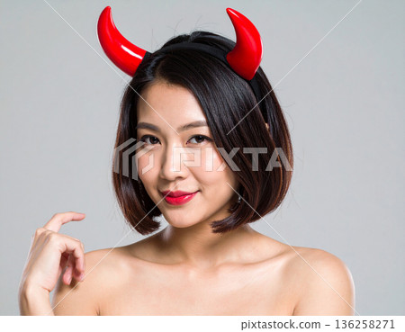 A young woman wearing devil horns as a Halloween costume 136258271