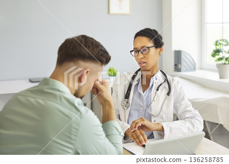 Female doctor counseling stressed male patient during appointment at modern clinic 136258785