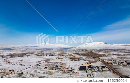 A snowy landscape with a few houses in the distance A snowy landscape with a few houses in the distance 136259014