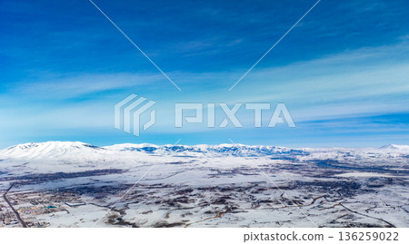 A snowy mountain range is visible in the distance, with a clear blue sky above A snowy mountain range is visible in the distance, with a clear blue sky above 136259022