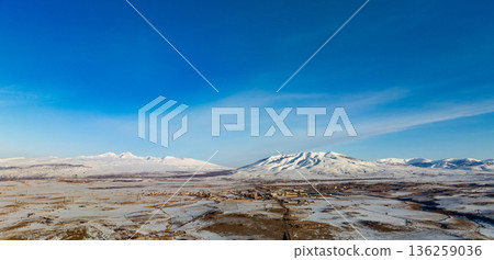 A snowy mountain range is visible in the distance, with a clear blue sky above A snowy mountain range is visible in the distance, with a clear blue sky above 136259036