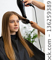 A woman with long brown hair is getting her hair blow dried by a stylist 136259389